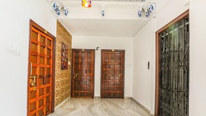 Un pasillo con tres puertas de madera, una pared de piedra y un suelo de mármol.
