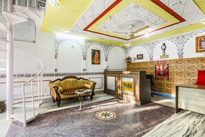 A hotel lobby with a marble floor, a reception desk, a sofa, and a staircase. - Hotel Pichola Haveli (Udaipur)