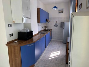 Eine Küche mit blauen Schränken, einer Mikrowelle, einem Herd und einem Kühlschrank.