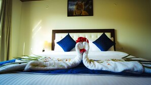 A hotel room with a bed, a painting of a tiger on the wall, and towels arranged on the bed.