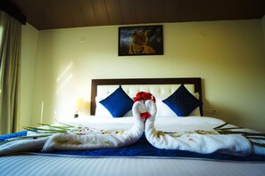 A hotel room with a bed, a painting of a tiger on the wall, and towels arranged on the bed.
