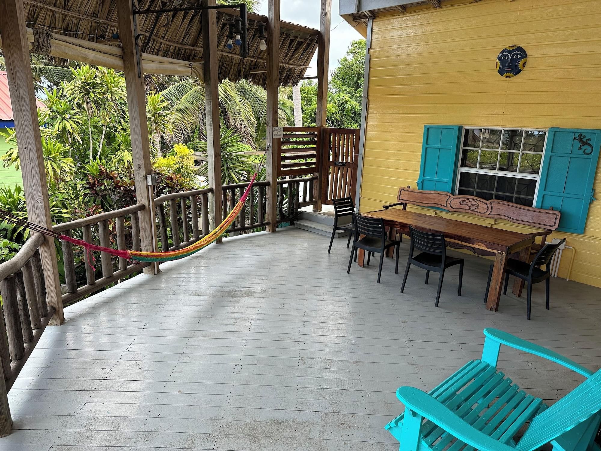 A wooden deck with a hammock, a table with chairs, and a turquoise bench.