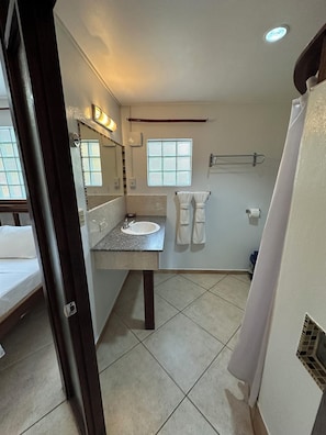 A bathroom with a sink, mirror, towel rack, and a window. - All Seasons Guest House (Hopkins)