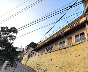 A multi-story building with balconies, a yellow exterior wall, and numerous power lines overhead. - Sangam By Stotrak - Mussoorie (Dehradun)