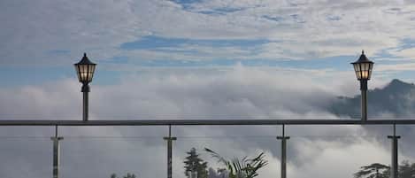 Una terraza con sillones de mimbre, una mesa y dos farolas.