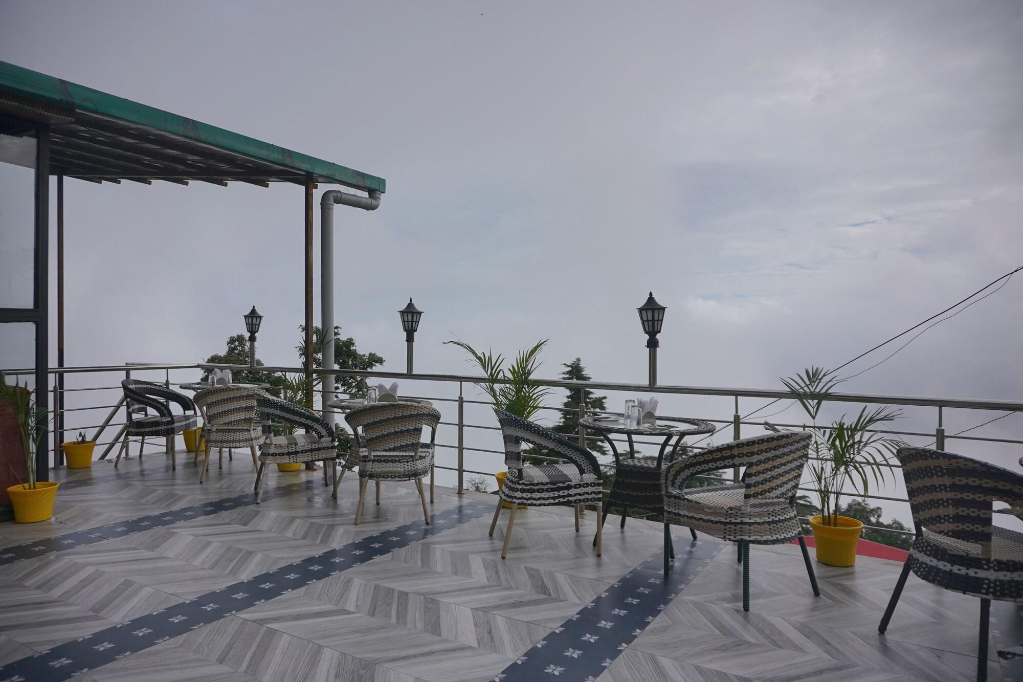 Une terrasse avec des chaises et des tables en osier, des plantes en pot et une vue sur le ciel.