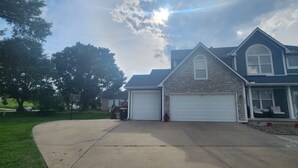 A residential house with two garages, a stone facade, and a large tree in the yard. - CLOSE TO STADIUM! 2-bdroom lower level open-concept home (Kansas City)