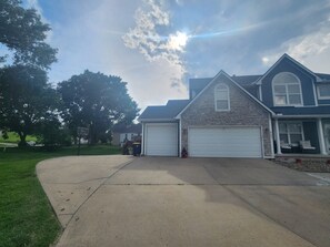 A residential house with two garages, a stone facade, and a large tree in the yard. - CLOSE TO STADIUM! 2-bdroom lower level open-concept home (Kansas City)