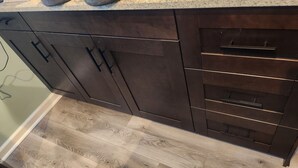 A kitchen with dark wooden cabinets, a light wood floor, and a countertop. - CLOSE TO STADIUM! 2-bdroom lower level open-concept home (Kansas City)