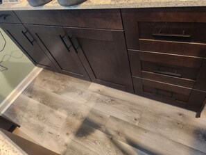 A kitchen with dark wooden cabinets, a light wood floor, and a countertop. - CLOSE TO STADIUM! 2-bdroom lower level open-concept home (Kansas City)