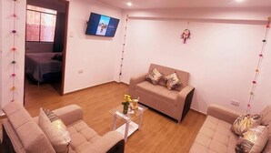 A living room with a sofa set, a coffee table, and a TV mounted on the wall. - APARTMENTS ALEXIA HOUSE ENJOY A COMFORTABLE AND COZY STAY IN CUSCO (Cusco)