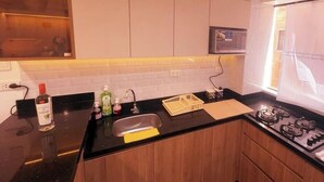 A modern kitchen with a black countertop, stainless steel sink, and a gas stove. - APARTMENTS ALEXIA HOUSE ENJOY A COMFORTABLE AND COZY STAY IN CUSCO (Cusco)