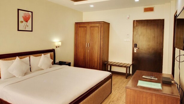 Ein Hotelzimmer mit einem großen Bett, einem Holzschrank, einem Nachttisch und einem Schreibtisch mit Stuhl.