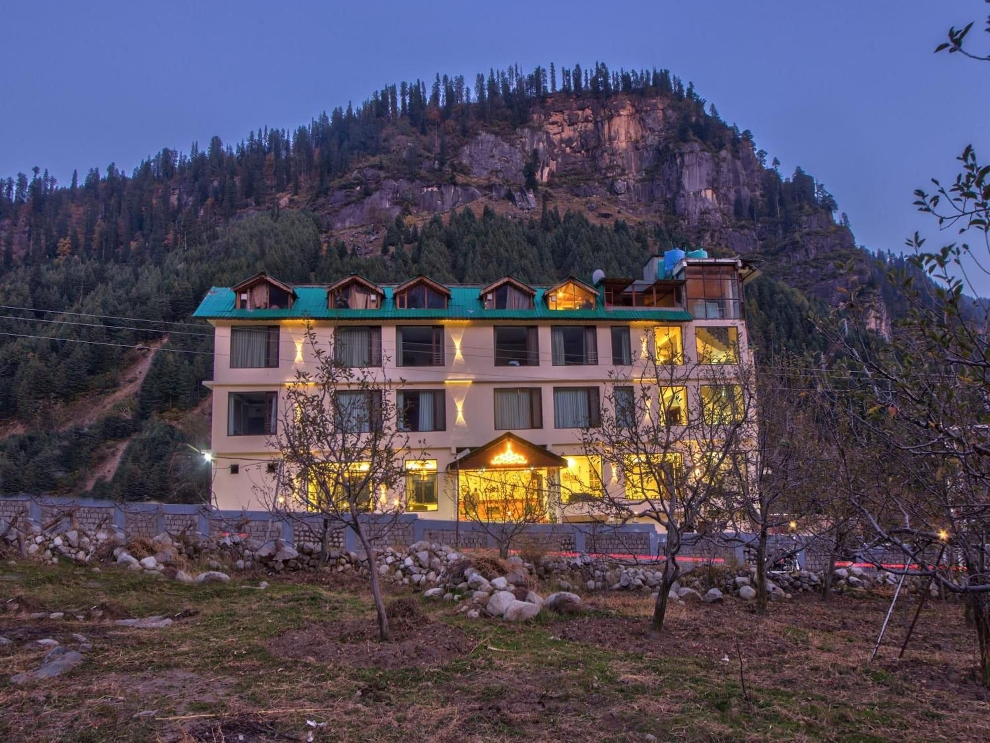A multi-story hotel with a mountain backdrop, featuring a prominent entrance and multiple windows.