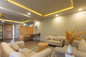A modern living room with a sofa, a round coffee table, and a decorative vase. - Stone Hedge Hotel Hunder (Leh)