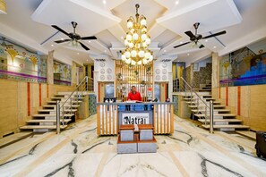 A hotel lobby with a reception desk, multiple clocks, a chandelier, ceiling fans, and marble flooring. - Hotel Natraz New Delhi (New Delhi)