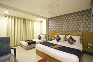 A hotel room with two beds, a ceiling fan, a patterned wall, and a window with curtains. - Hotel Natraz New Delhi (New Delhi)