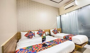 A hotel room with two beds, a large mirror, an air conditioning unit, and a view of a building outside. - Fabexpress Marol Metro (Mumbai)