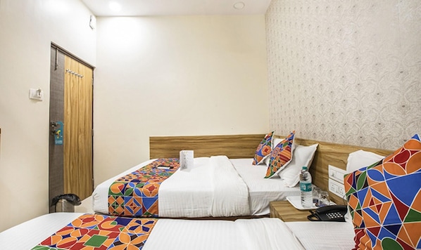 A hotel room with two beds, a wooden headboard, a patterned wall, and a door with a towel rack. - Fabexpress Marol Metro (Mumbai)