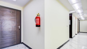 Un couloir avec un extincteur fixé au mur, une porte portant l’inscription « 301 », et un sol carrelé.