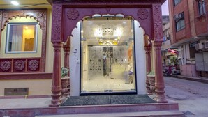 L’entrée d’un hôtel de caractère, avec des piliers richement décorés, une porte en verre et une enseigne au-dessus.