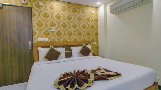 Une chambre d’hôtel avec un lit, une tête de lit en bois, un mur à motifs et un appareil de climatisation.