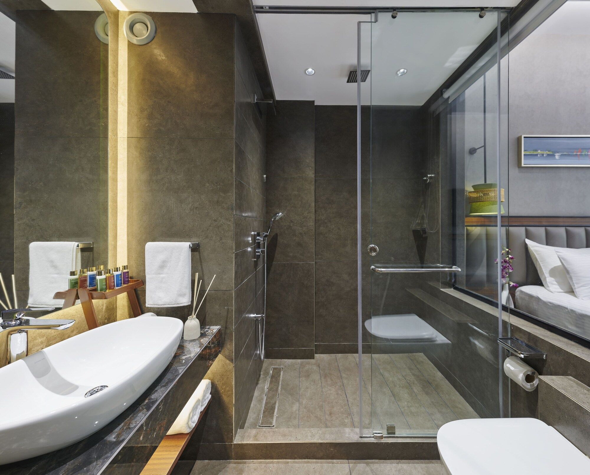 A modern bathroom with a glass shower enclosure, a large sink, and a toilet.