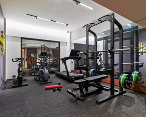A gym with exercise equipment, treadmills, and weightlifting stations. - Moyrah By Greenpark (Anjuna)