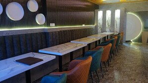 A modern restaurant with marble-topped tables, colorful chairs, and a patterned floor. - Hotel Grand Hill (Dalhousie)