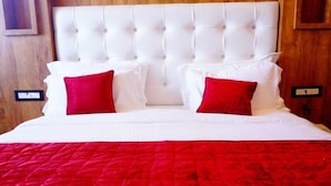 A bed with a tufted headboard, white bedding, and two red pillows. - Hotel Grand Hill (Dalhousie)