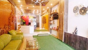 A room with a green sofa, a glass coffee table, a wooden ceiling, and a wall with decorative plates. - Hotel Grand Hill (Dalhousie)