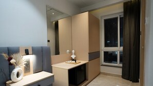 A modern bedroom with a bed, bedside table, mirror, and a window with curtains. - Hotel Kyzen (Hyderabad)