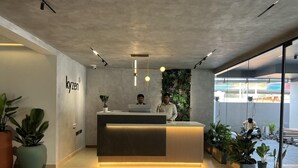 A reception desk with a modern design, a plant on the counter, and a wall with greenery. - Hotel Kyzen (Hyderabad)
