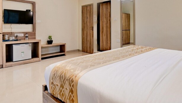 A bedroom with a bed, a TV, a desk, a wardrobe, and a ceiling fan. - Doves Kohinoor Exotica- Lonavala (Mawal)