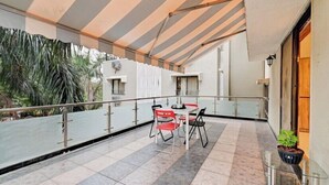 A balcony with a table and chairs, a potted plant, and a view of the surrounding area. - Doves Kohinoor Exotica- Lonavala (Mawal)
