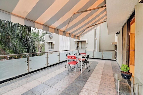 A balcony with a table and chairs, a potted plant, and a view of the surrounding area.