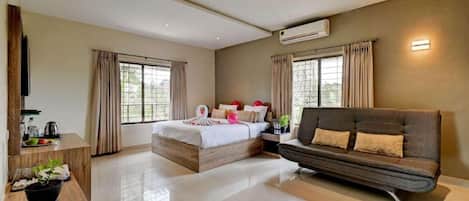 A hotel room with a bed, sofa, TV, and a dining area with a table and chairs.