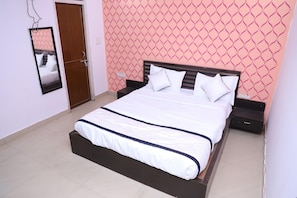 A bedroom with a bed, bedside tables, a mirror, and a door.