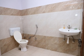 A bathroom with a toilet, shower, and sink.