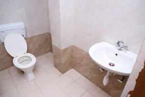 A bathroom with a toilet, sink, and tiled floor. - Hotel Axiom Prime (Lucknow)