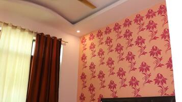 A bedroom with a bed, a ceiling fan, and a wall with a floral pattern.