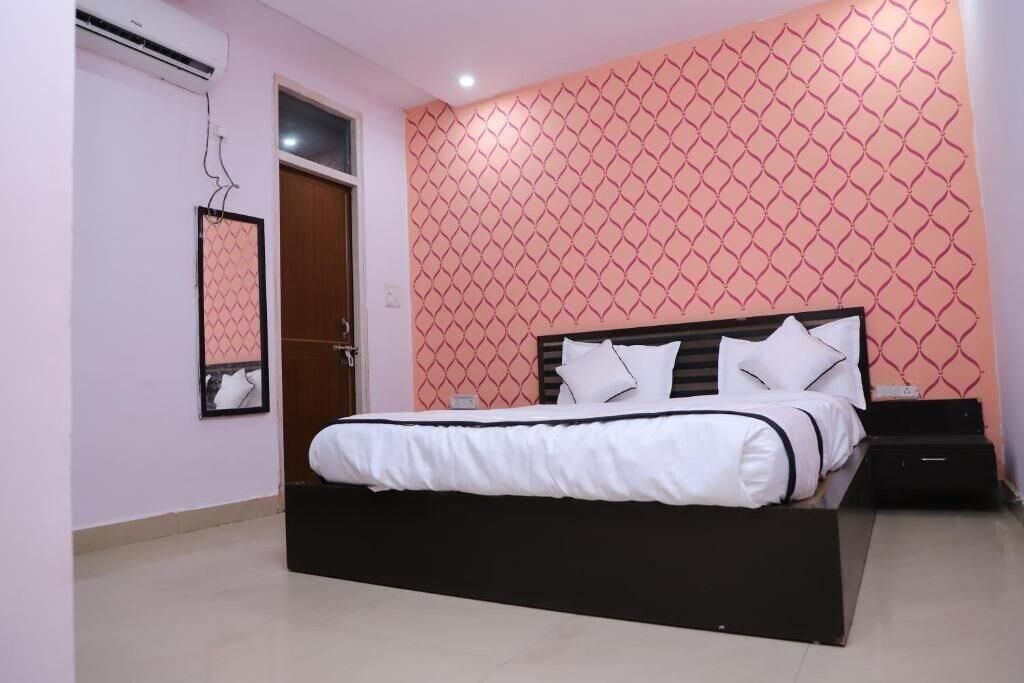 A bedroom with a bed, a nightstand, a mirror, and a door.