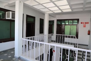 A corridor with white railings, doors with glass panels, and a fire extinguisher on the wall. - Hotel Axiom Prime (Lucknow)