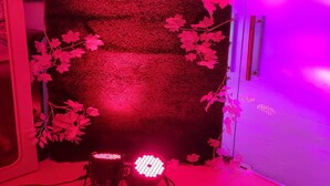 Quarto com parede texturizada, tapeçaria pendurada e pequena mesa com uma luminária.
