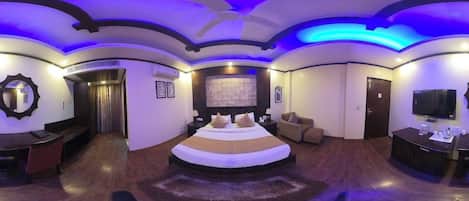 Quarto circular com uma cama, televisão e área de estar.