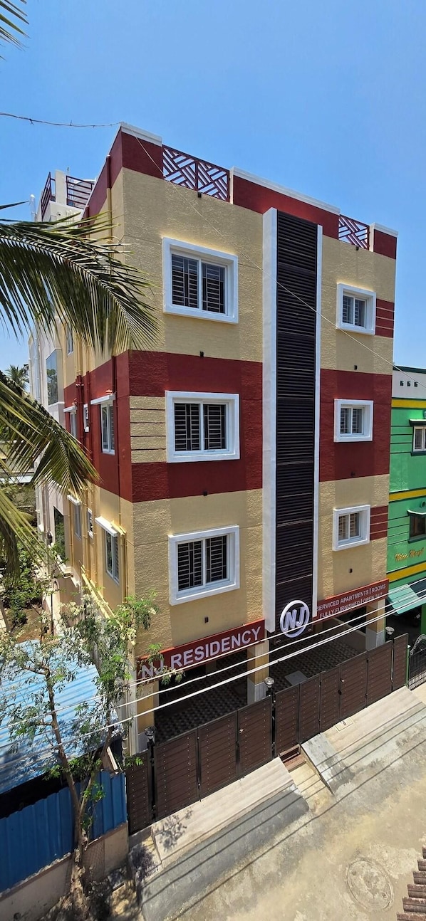 A multi-story residential building with a central vertical feature, balconies, and a sign indicating it is a serviced apartment. - Nj Residency (Chennai)