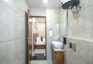 A modern bathroom with a large sink, a mirror, and a shower. - One Earth Elegant (Yamkeshwar)