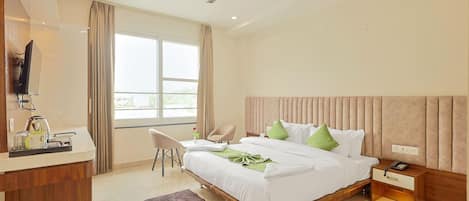 A hotel room with a bed, bedside table, chair, desk with a telephone, and a ceiling fan.
