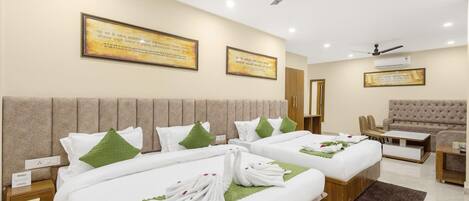 A hotel room with two beds, a sofa, a chair, and a ceiling fan.