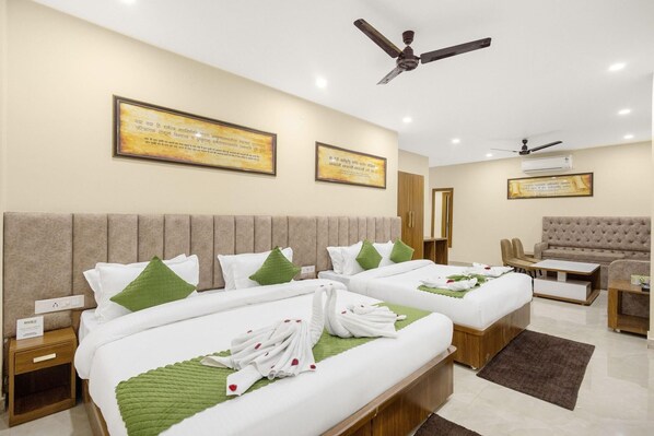 A hotel room with two beds, a sofa, a chair, and a ceiling fan. - One Earth Elegant (Yamkeshwar)